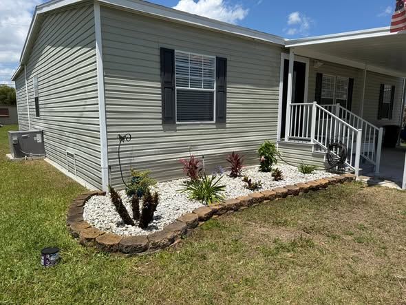 After: fresh decorative rock bed with a natural stone border and new tropical plantings